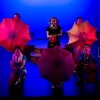 Six people standing on a stage with umbrellas open