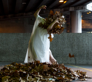 A woman in white dress. She is standing in a pile of flowers and also holding them in her arms